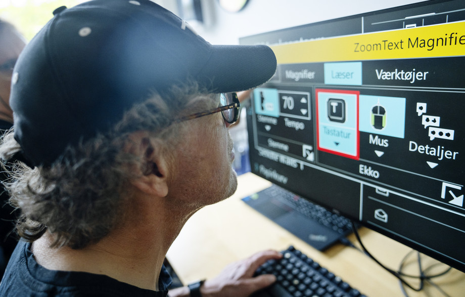 En svagsynet borger, som træner synskompenserende software på en computer, hvor skærmindhold bl.a. kan forstørres og farverne kan ændres. Foto: IBOS
