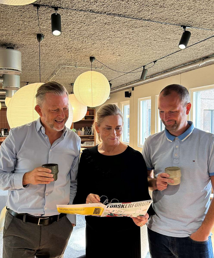 Two men and a woman looking at a document