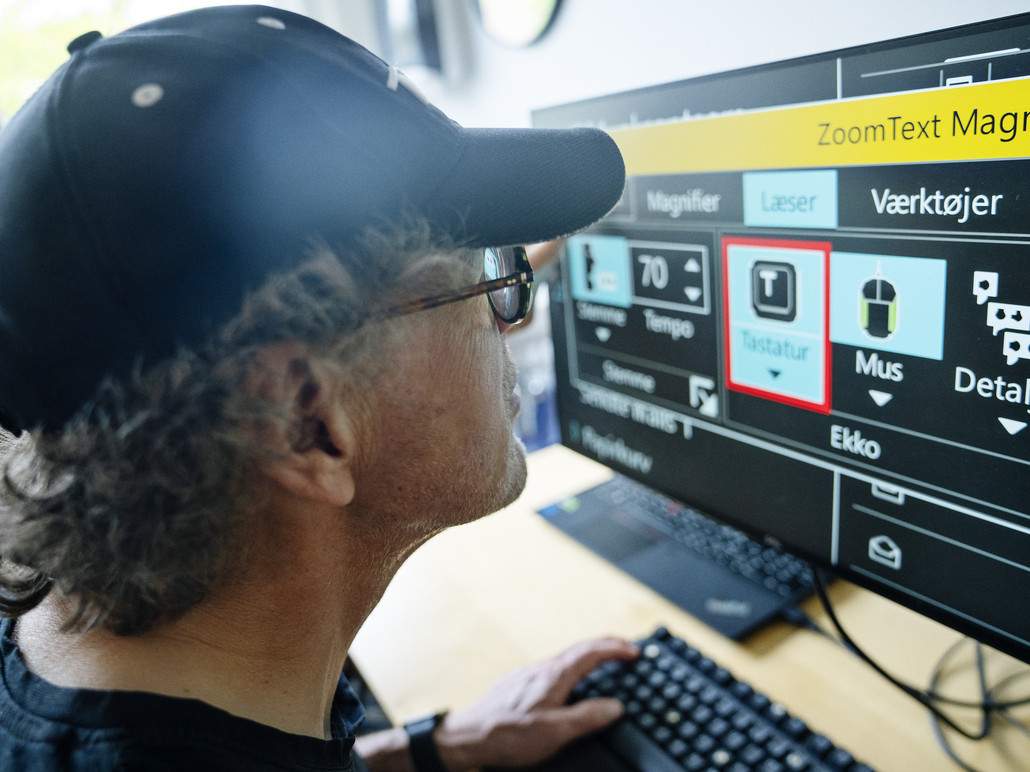 En svagsynet borger, som træner synskompenserende software på en computer, hvor skærmindhold bl.a. kan forstørres og farverne kan ændres. Foto: IBOS